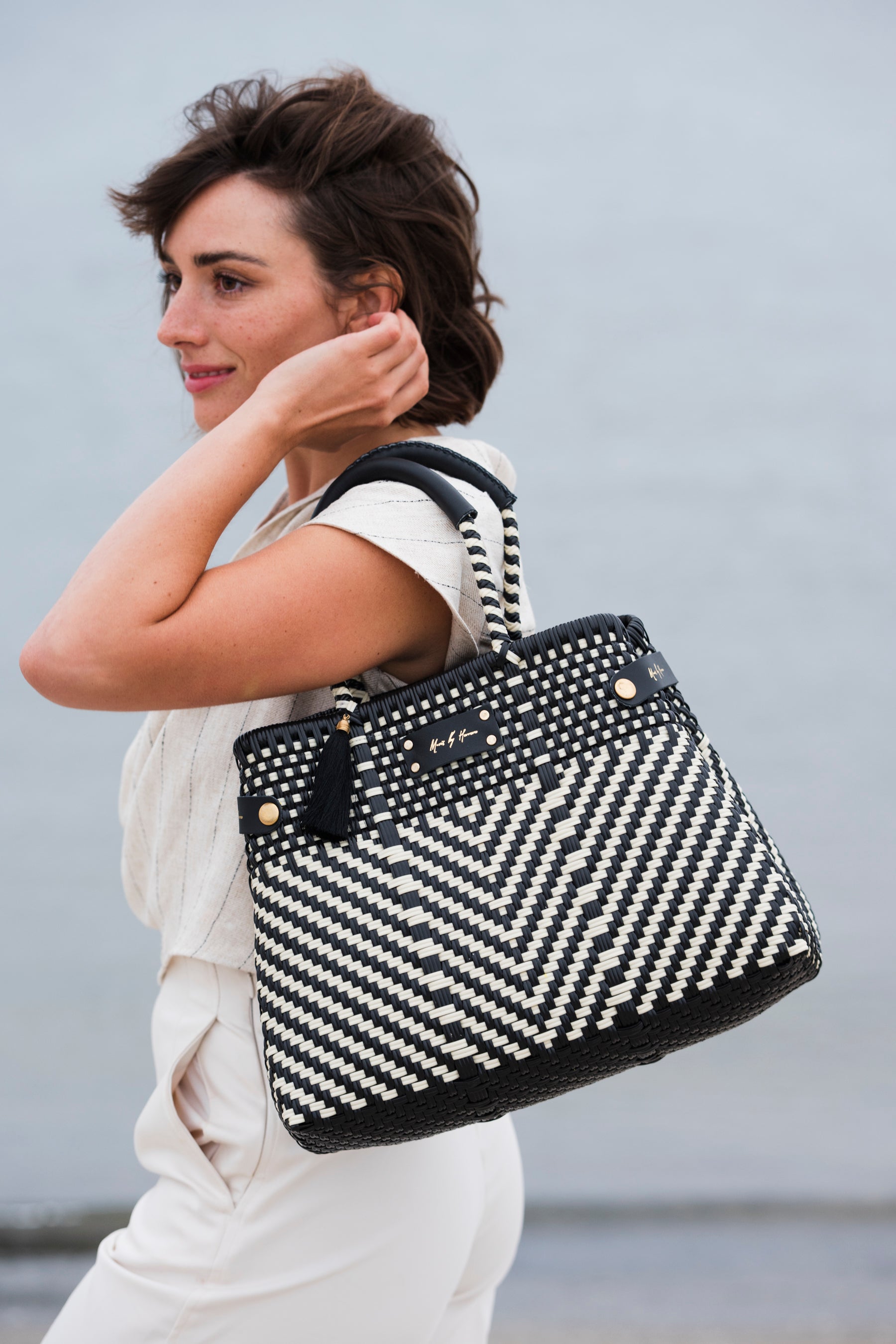 Woman holding a black and white patterned handbag against a light background