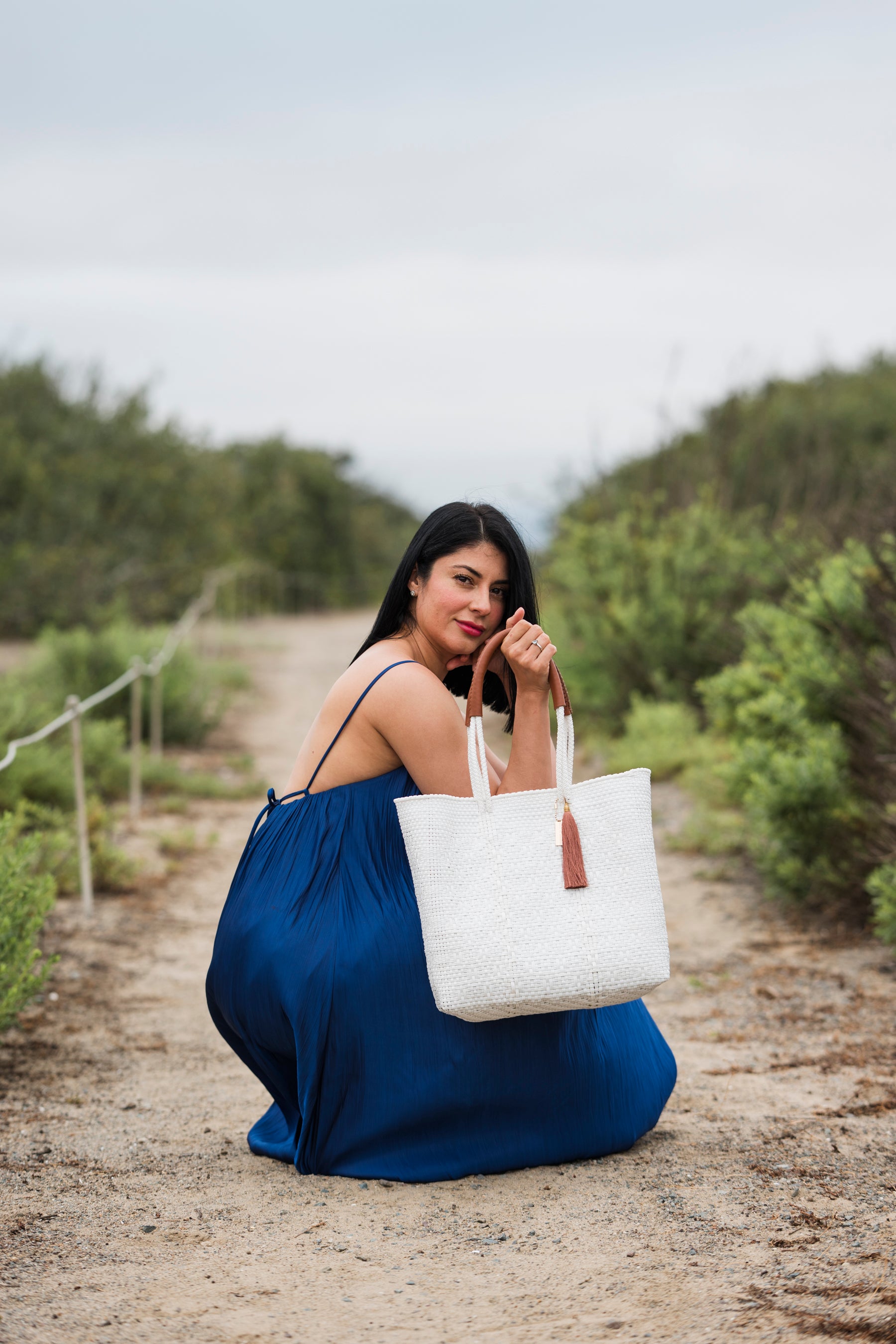 Woman holding the White Pearl Tote Bag – luxury handwoven white eco-friendly resort tote made from sustainable materials.