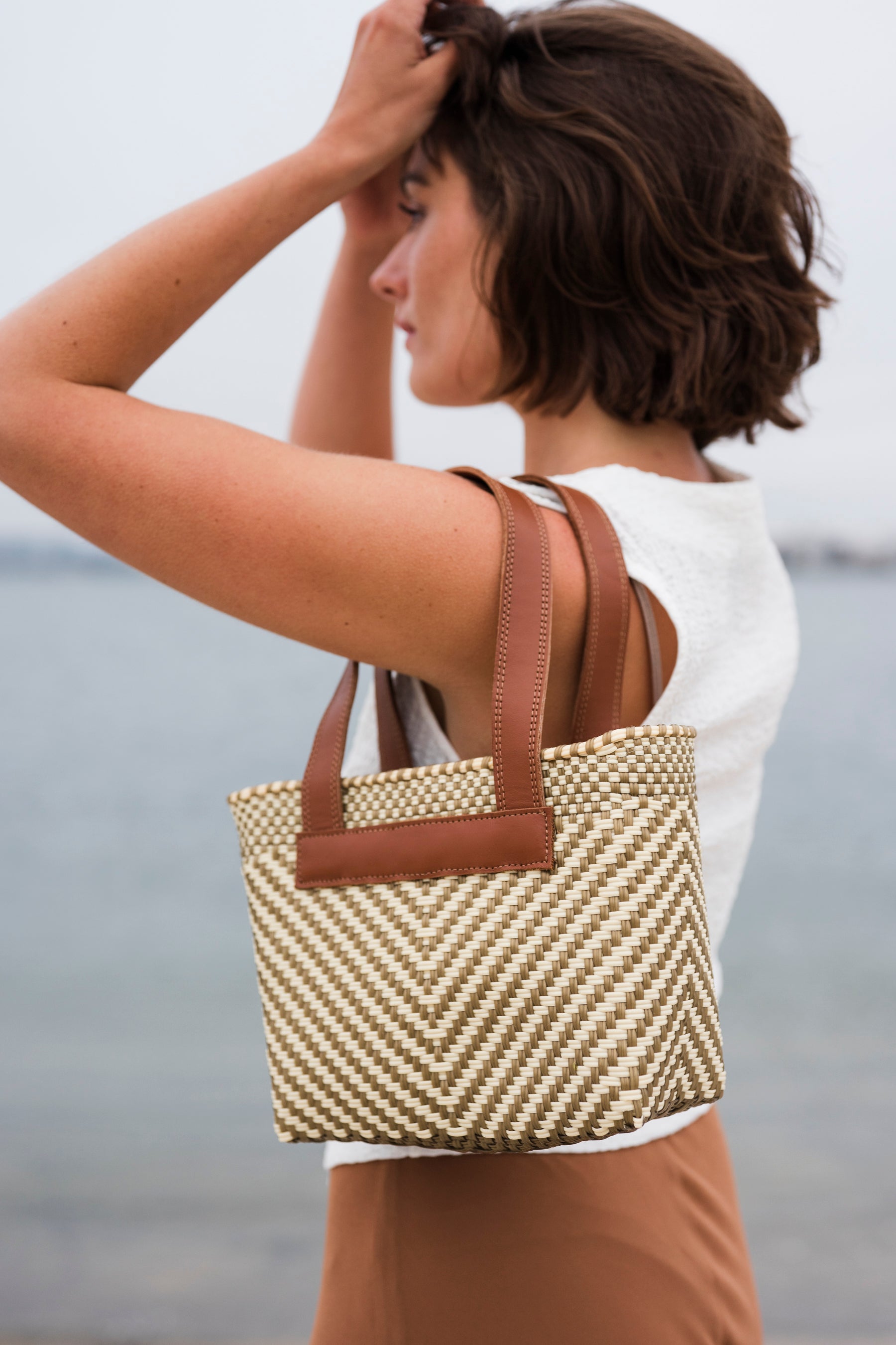 Woman holding a handwoven mini tote bag in ivory and brown color