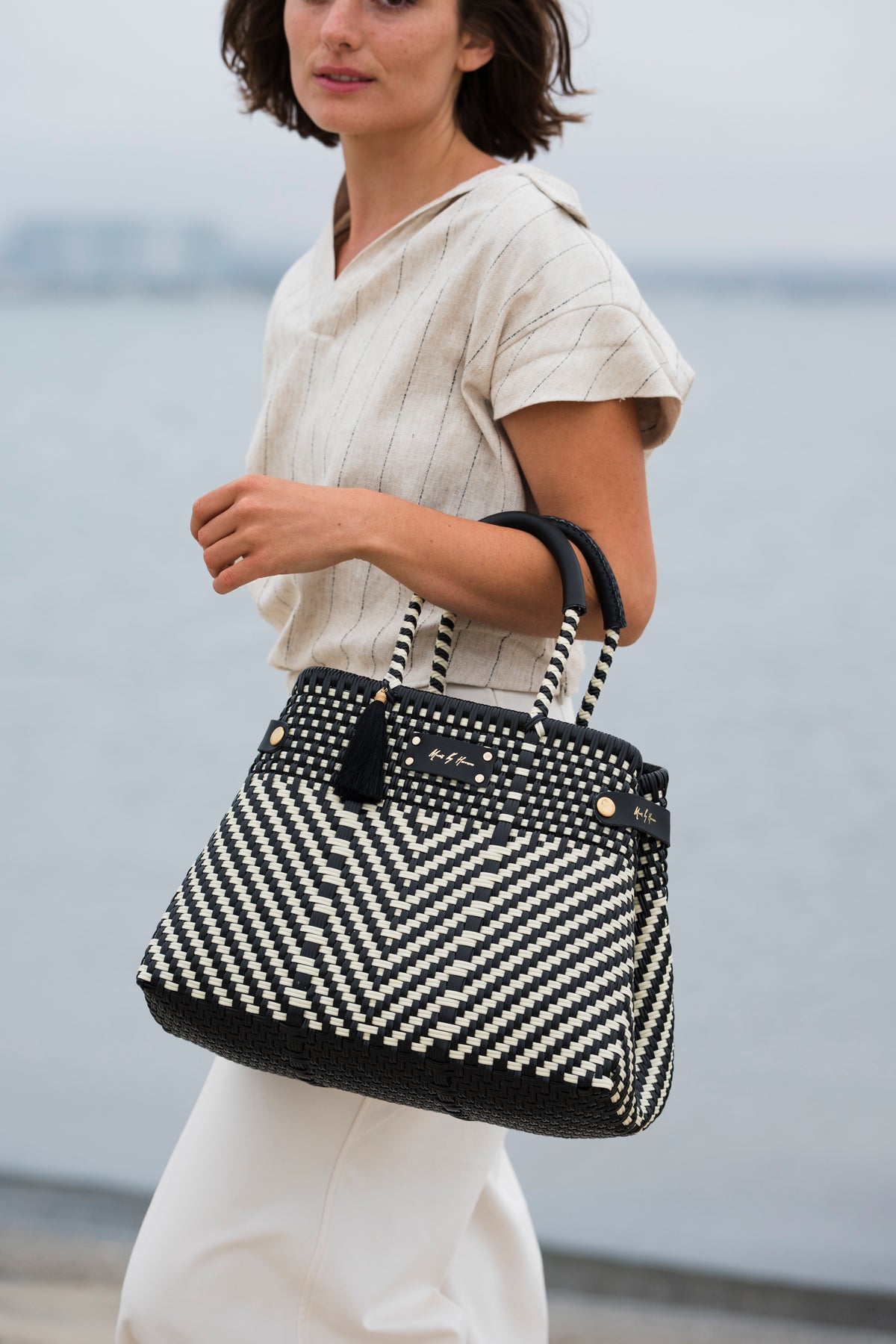 MAVIS BY HERRERA Digital Gift Card: woman carrying an ivory and black chevron-woven handbag.