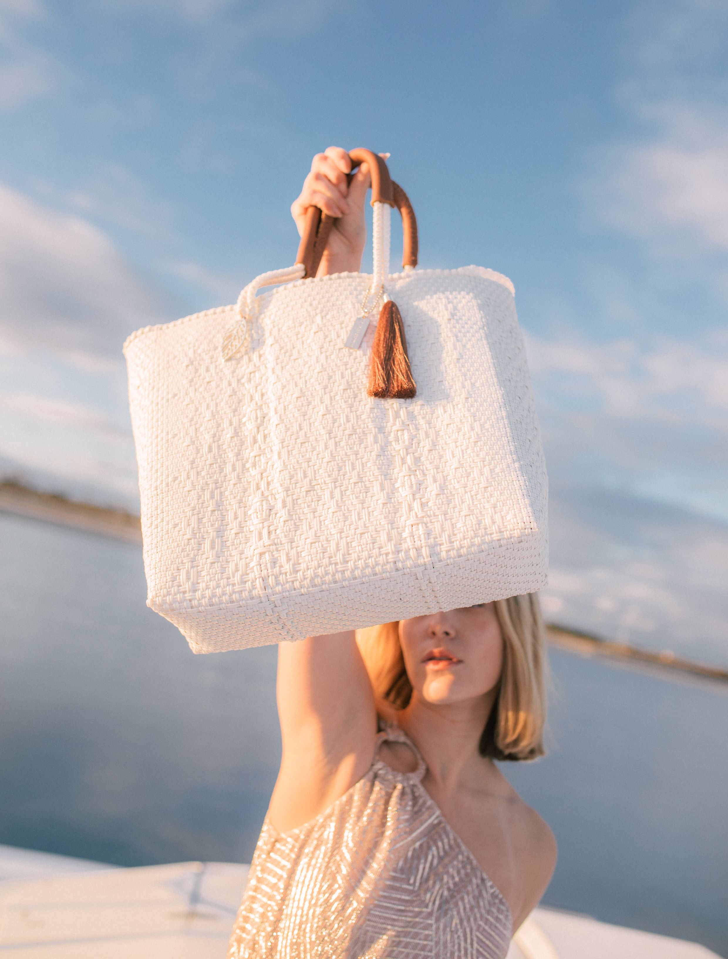 Woman holding the White Pearl Tote Bag – luxury handwoven white eco-friendly resort tote made from recycled plastic.