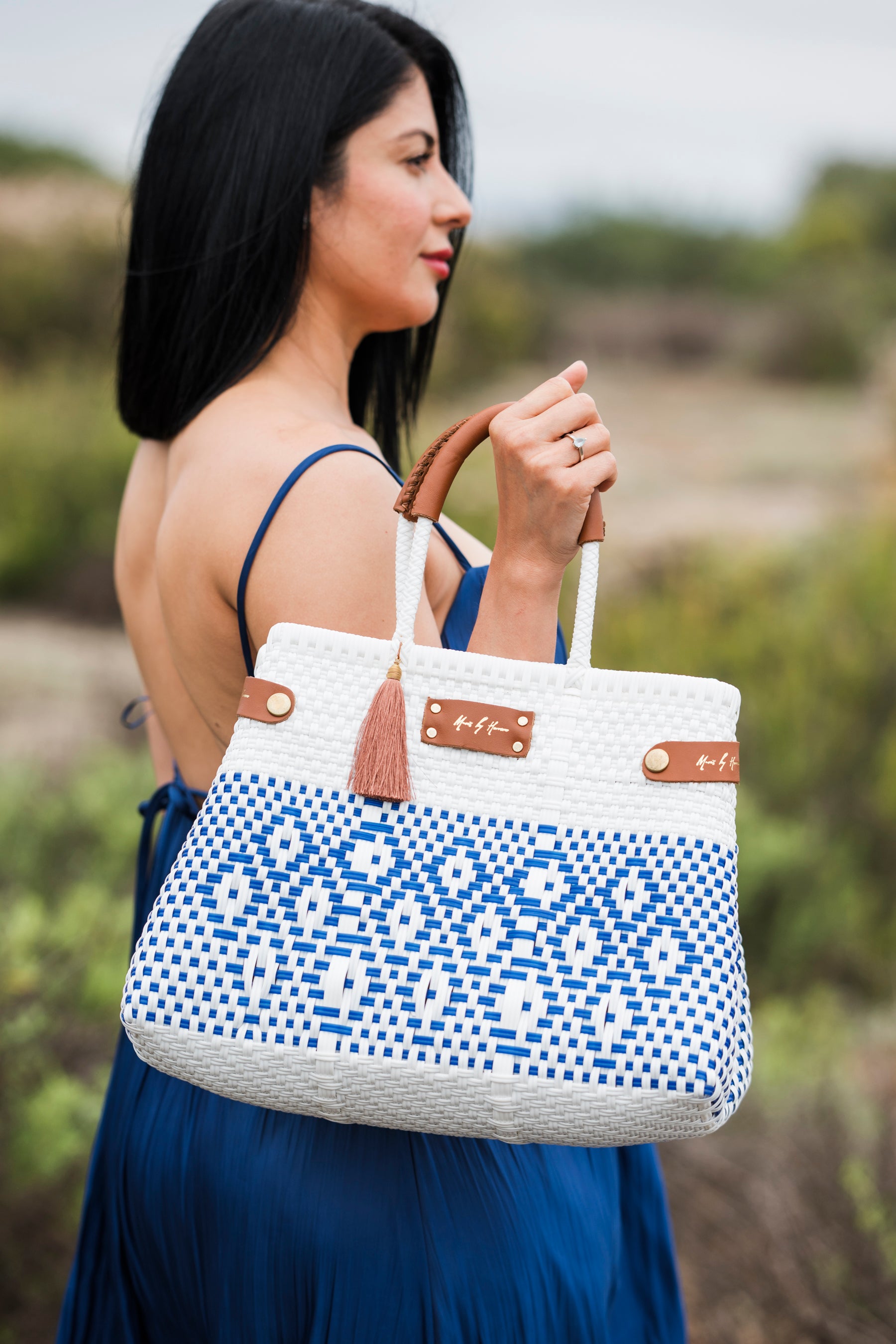 Woman holding a blue and white patterned handbag with a blurred natural background
