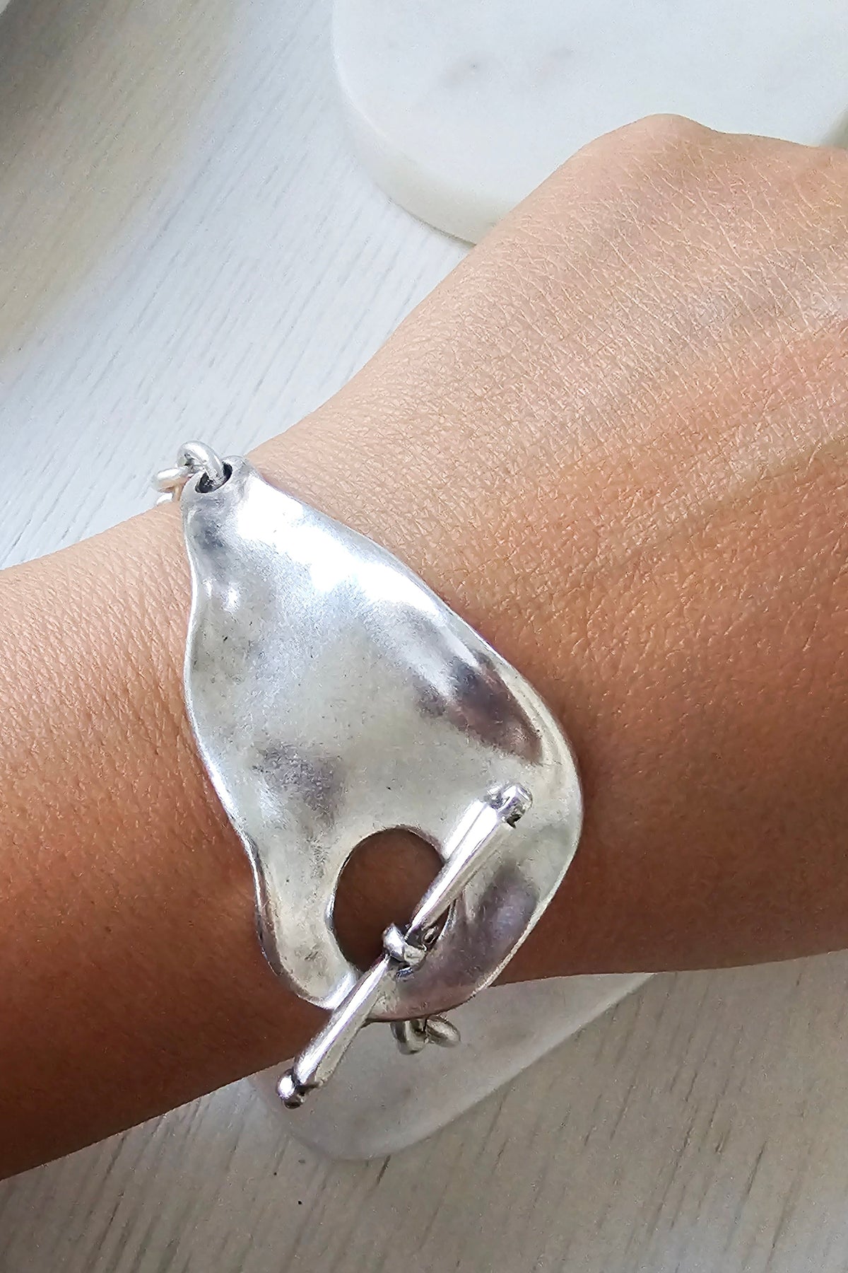 Eclat Bracelet: model wearing a sculptural silver-tone bracelet.