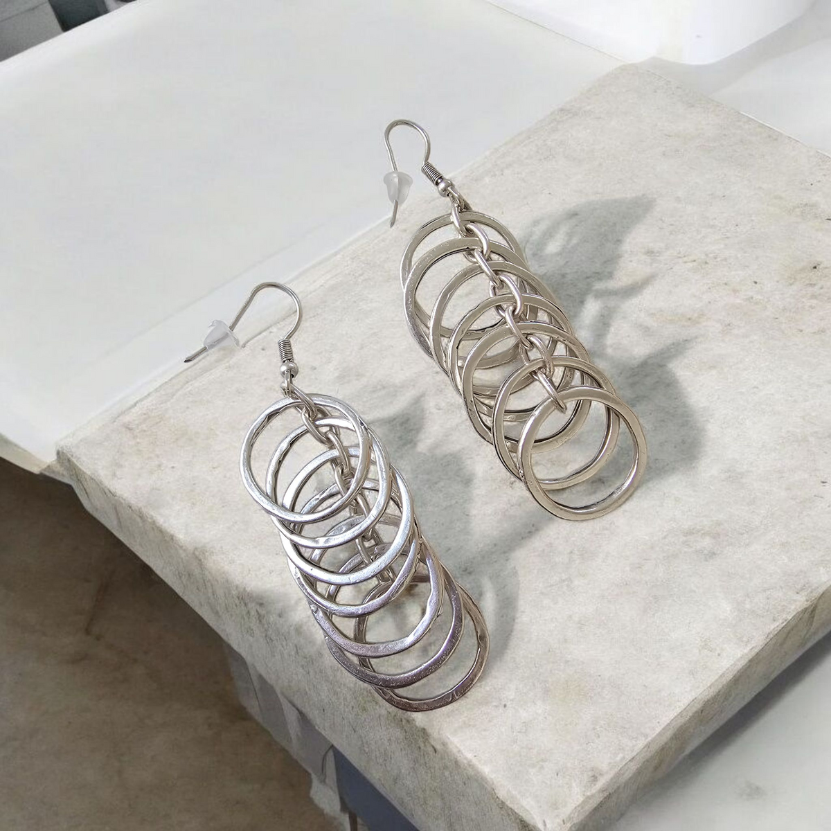 Halo Cascade Earrings: silver-tone cascading circle earrings, angled view.