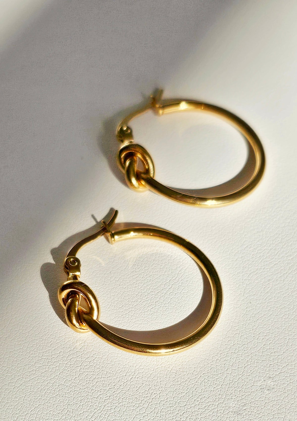 Love Knot Hoop Earrings: gold-tone knotted hoop earrings, angled view.