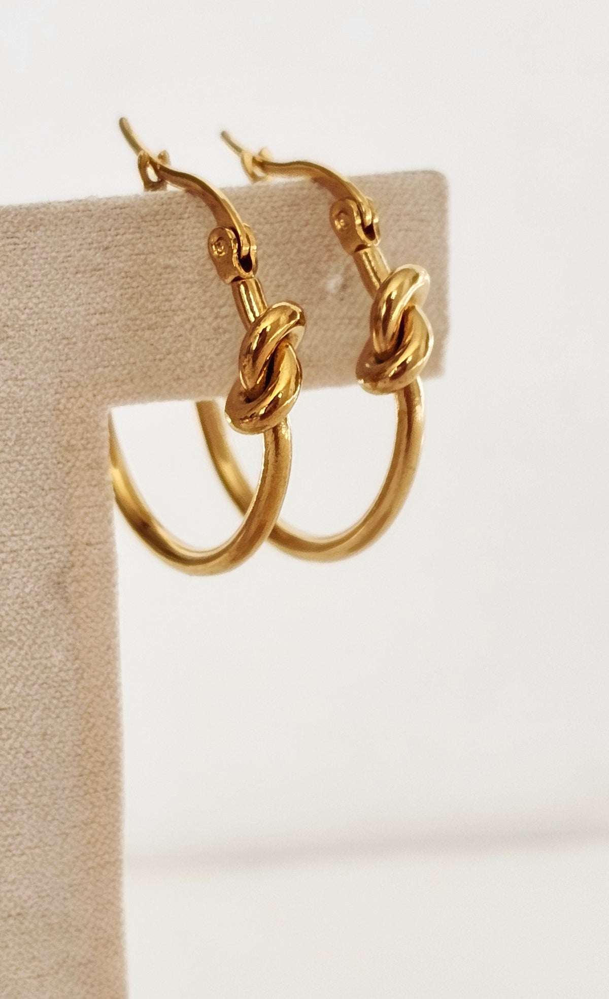 Love Knot Hoop Earrings: gold-tone hoop earrings with knot details, side view.