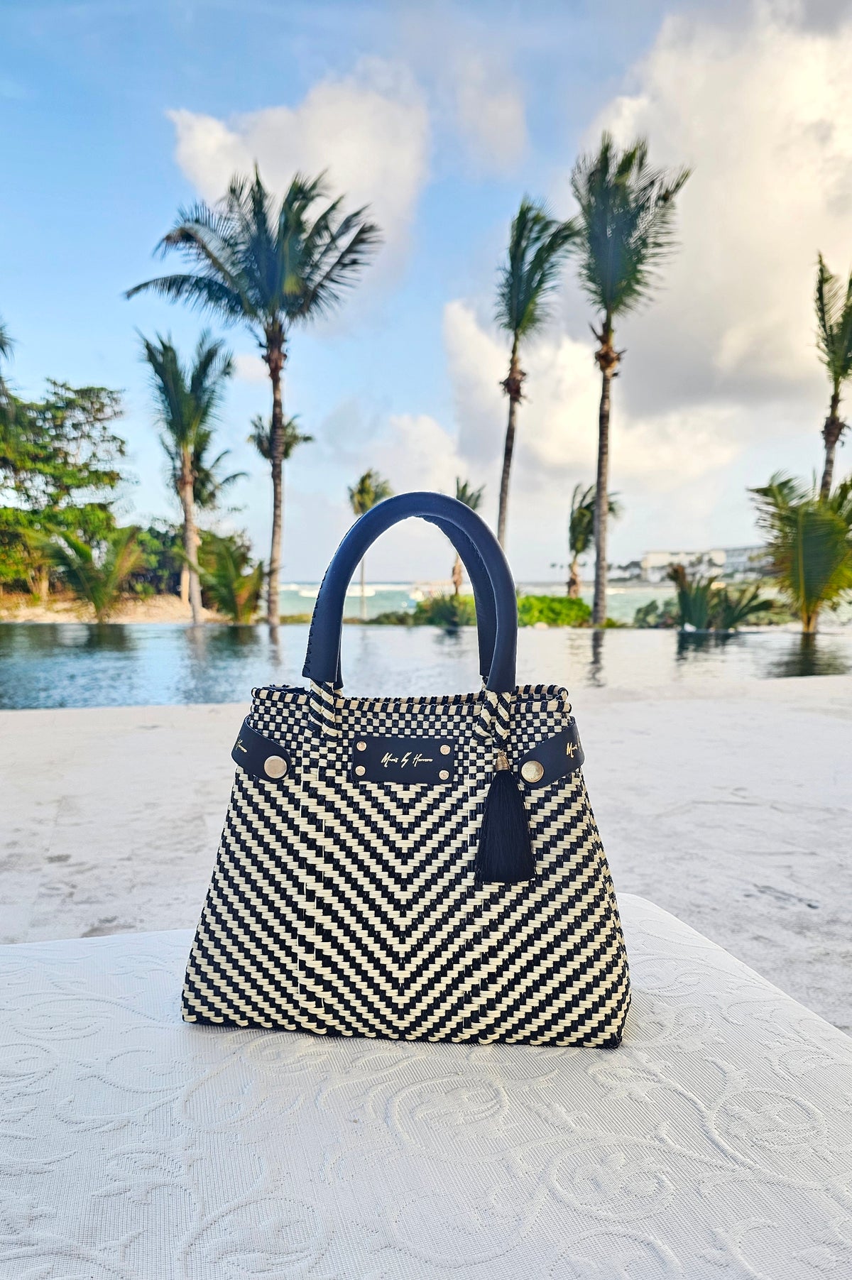 Mini Less Pollution Convertible Crossbody Bag - Ivory Black Luxe: ivory and black handwoven mini convertible bag photographed outdoors beneath palm trees.