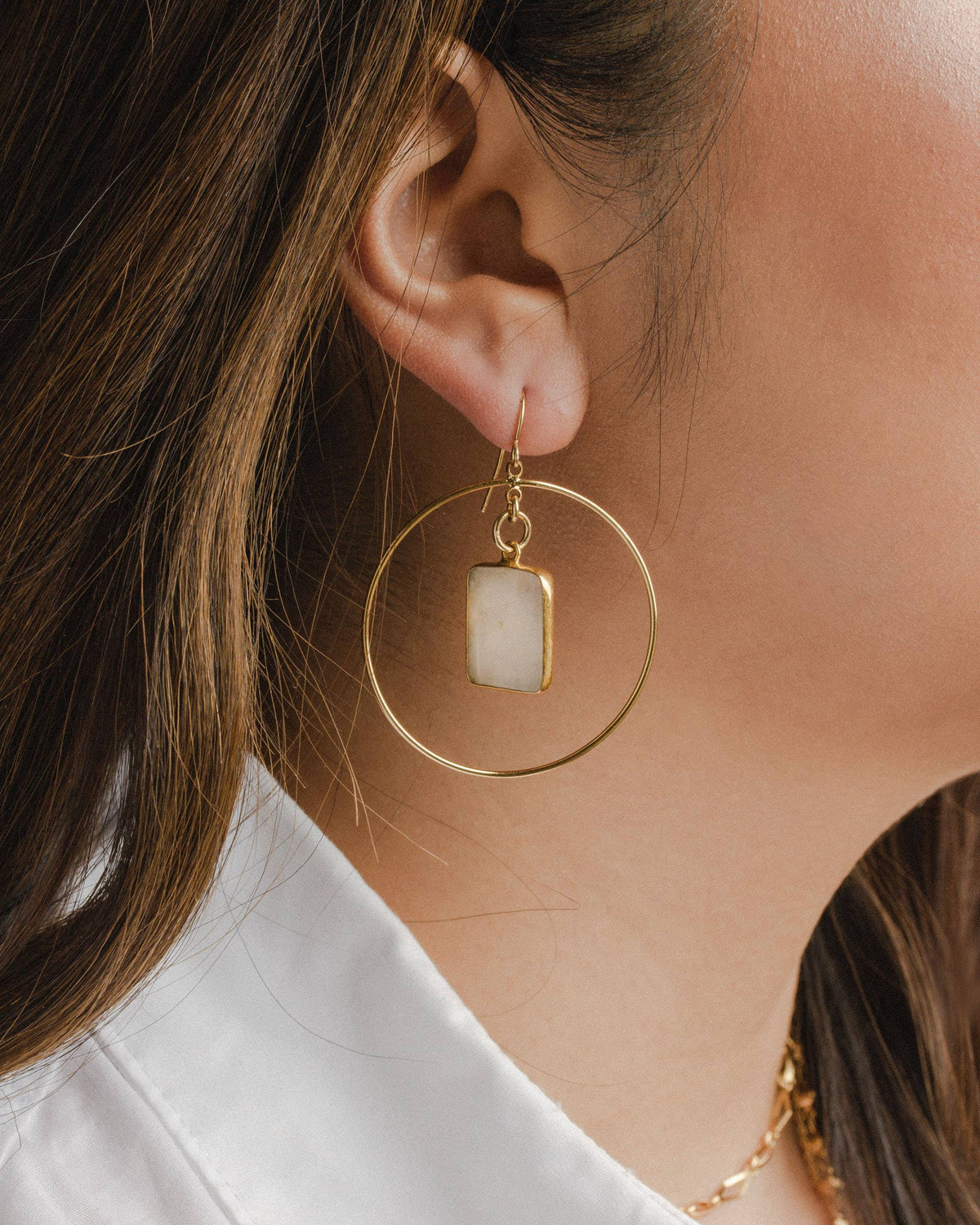 Moonstone Hoop Earrings: model wearing hoop earrings with rectangular pale stone pendants.