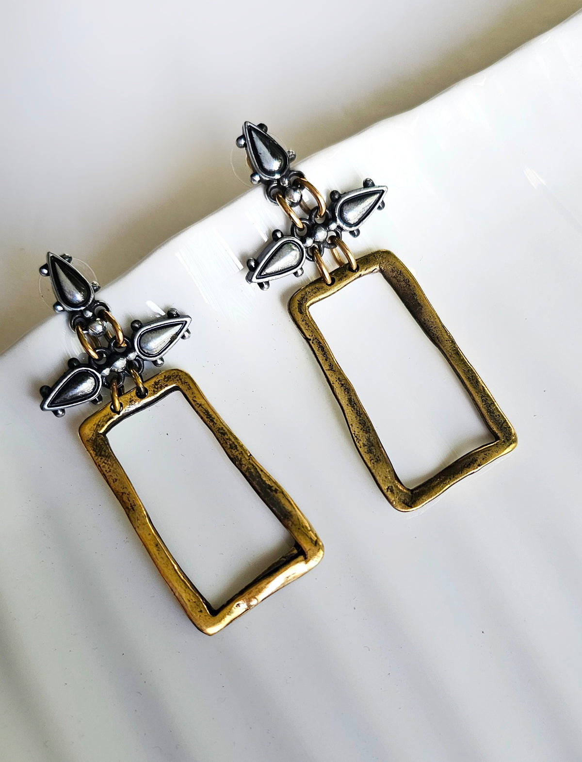 Sculpted Elegance Earrings: rectangular open-frame earrings with gold-tone borders and silver-tone accents, angled view.