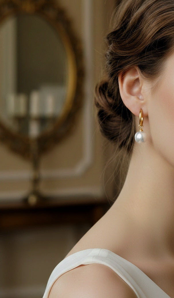 The Essential Pearl Earrings: model wearing pearl drop hoop earrings.